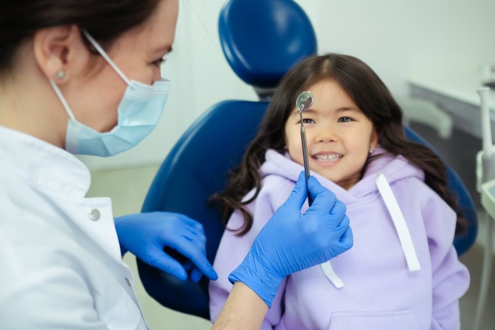 Niña conociendo un espejo dental durante una visita; fotografía ilustrativa